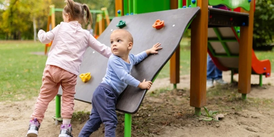 Dos niños jugando en un patio de recreo al aire libre
