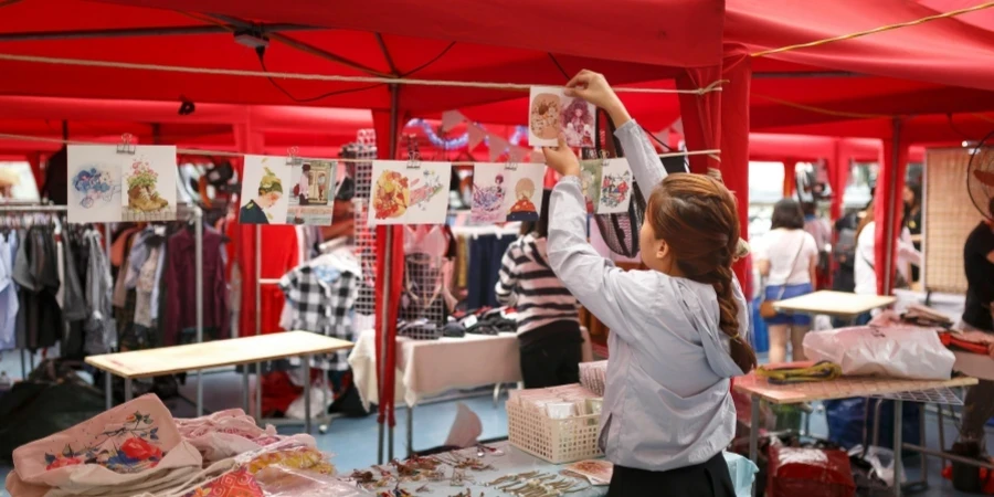 Mercado vibrante con carpas rojas, compradores y productos coloridos en exhibición.