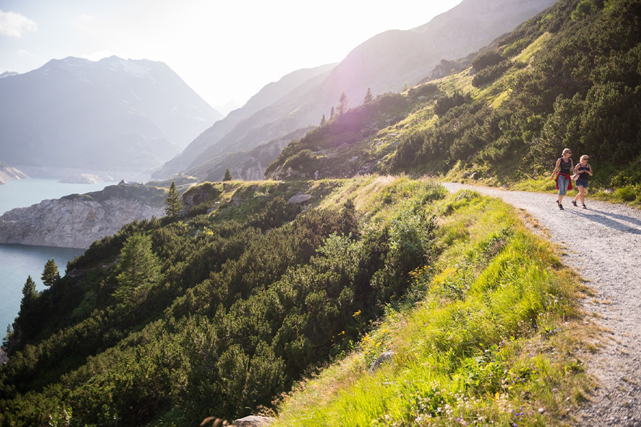 Zwei Frauen laufen mit Blick auf einen See und Berge