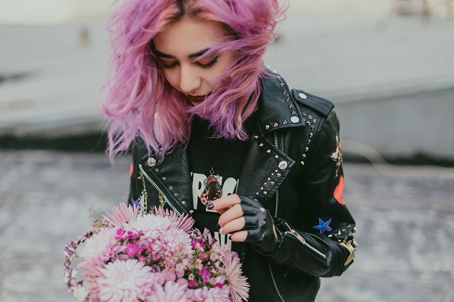 Dame mit rosa Haaren rockt schwarze Jacke mit mehreren Logos