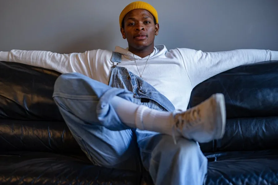 Man posing in a white shirt and denim dungarees