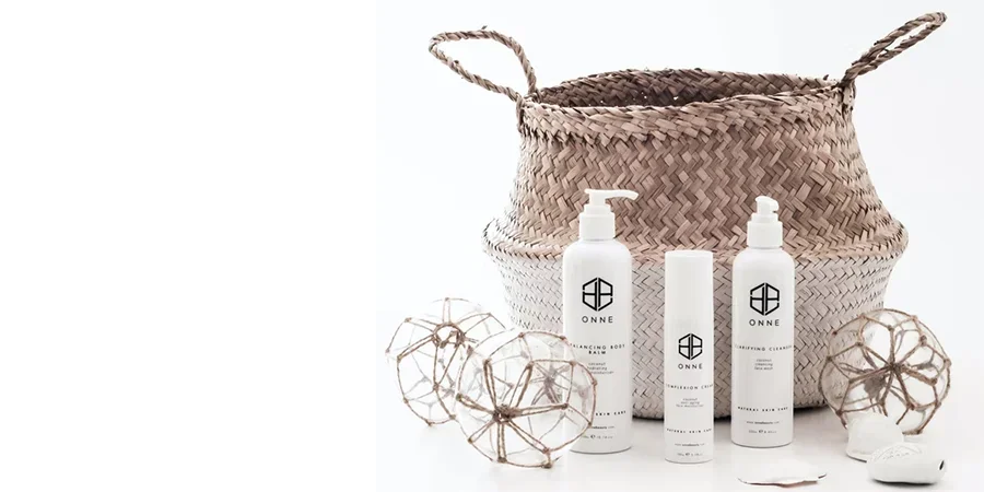 Three white skincare products in front of wicker basket