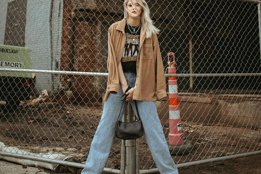 Linda loira balançando jeans soltos e jaqueta marrom