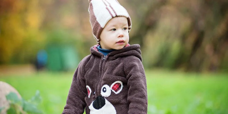 A toddler in a fleece jacket and head warmer