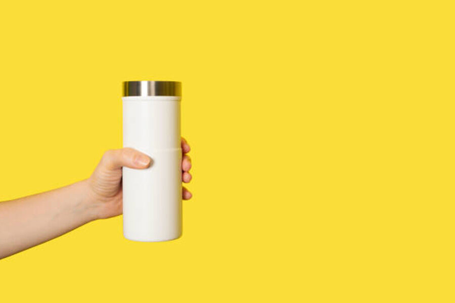 Un vaso de viaje blanco sobre un fondo amarillo