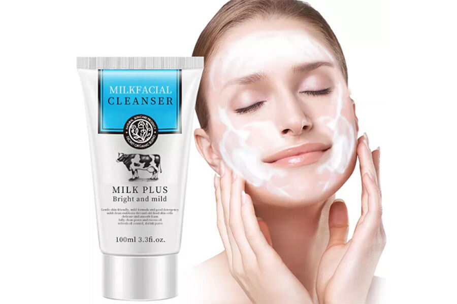 Eine Frau reibt sich mit einer Flasche neben sich ein Gesichtsreinigungsmittel ins Gesicht