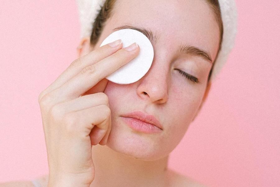 Woman removing makeup with reusable cotton pad