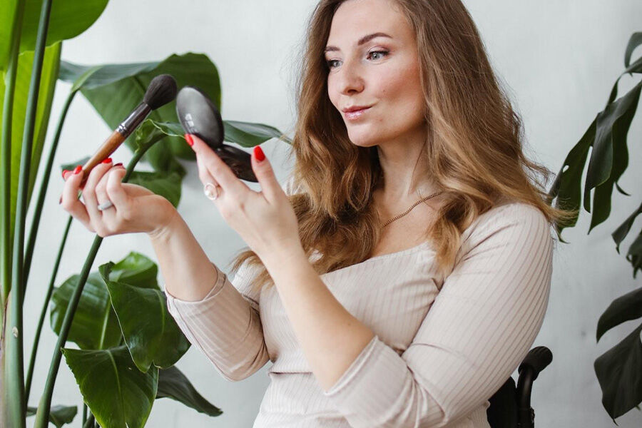 Женщина, сидящая в инвалидной коляске, наносит макияж