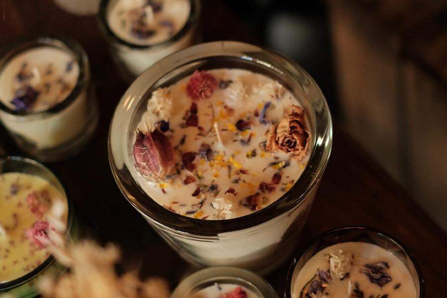 Candles with rose petals sit on a wooden countertop