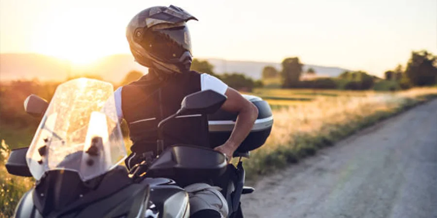 Man sitting on a motorcycle with helmet on at sunset