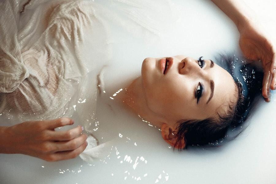 Woman soaking in a milk-colored bath
