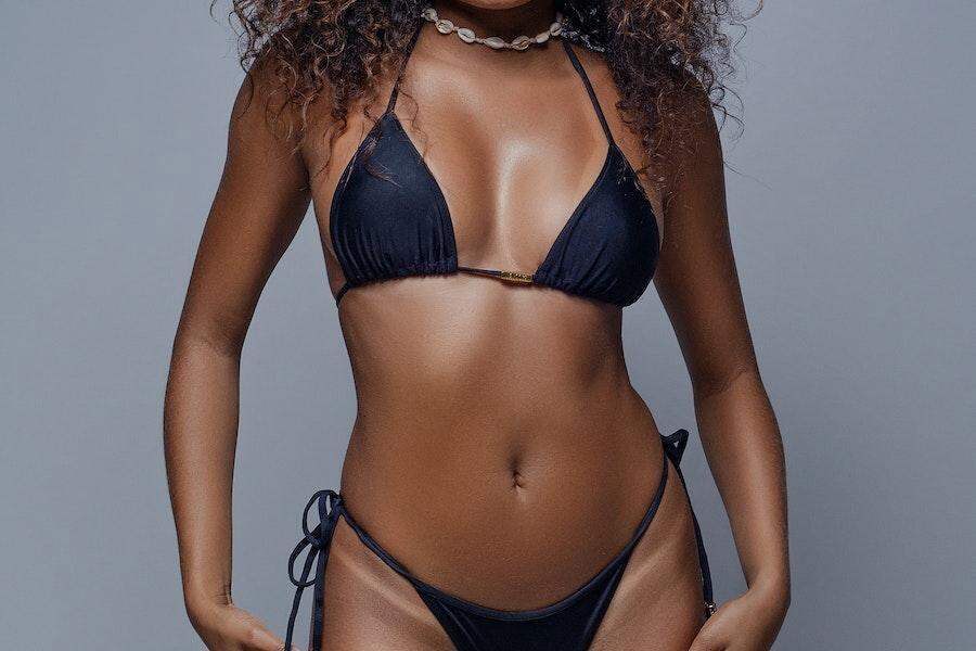 Темнокожая женщина позирует в купальниках с высокими ногами