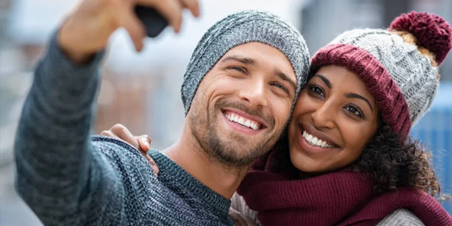 Man and woman wearing different styles of knitted beanies