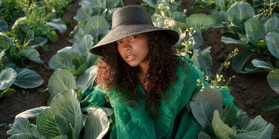 Woman posing near leaves with a black bucket hat