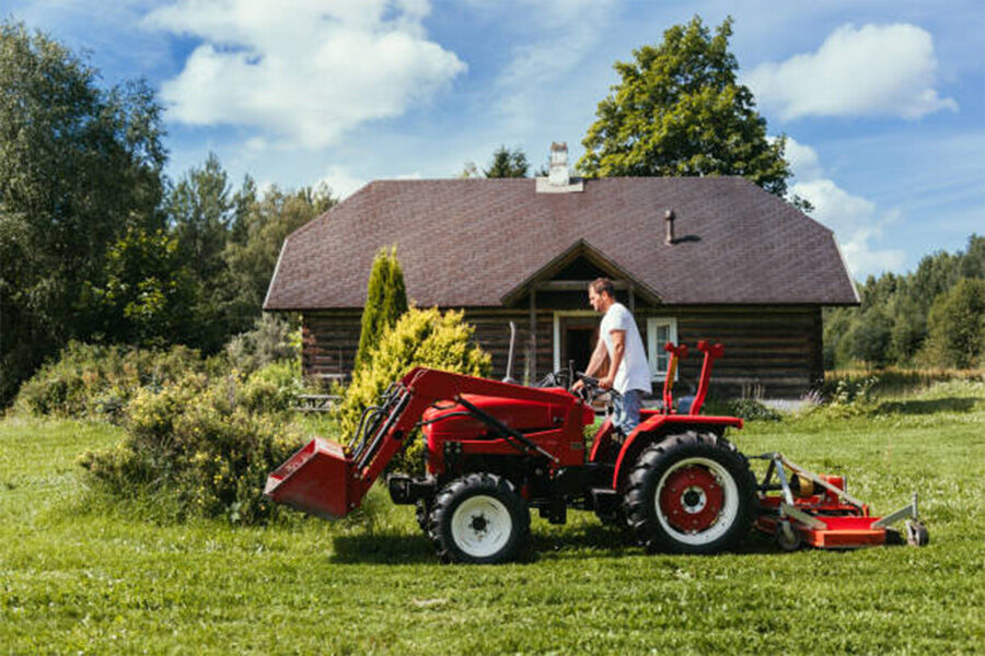 Un hombre en un tractor cortando hierba