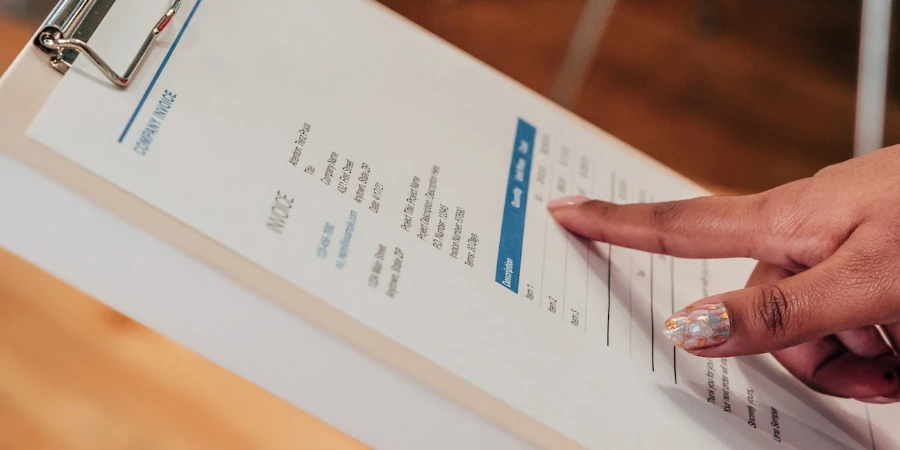 A person pointing at an invoice on a clipboard