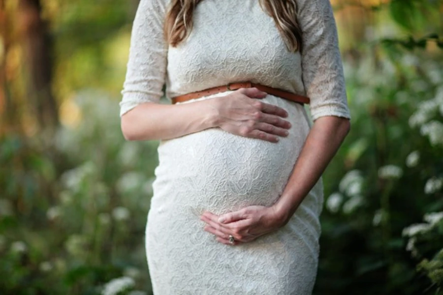 A pregnant woman wearing a lacy figure-framing maternity dress
