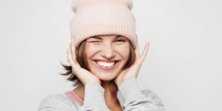 Funny young woman in a pink beanie hat makes faces