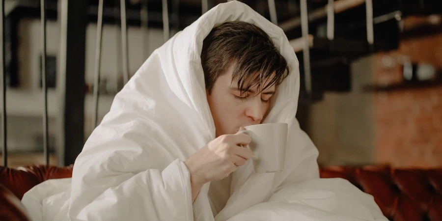 A man wrapped in a blanket sipping coffee