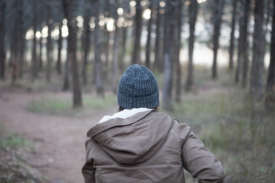 a-person-wearing-cuffed-beanie-and-running-amid-woods