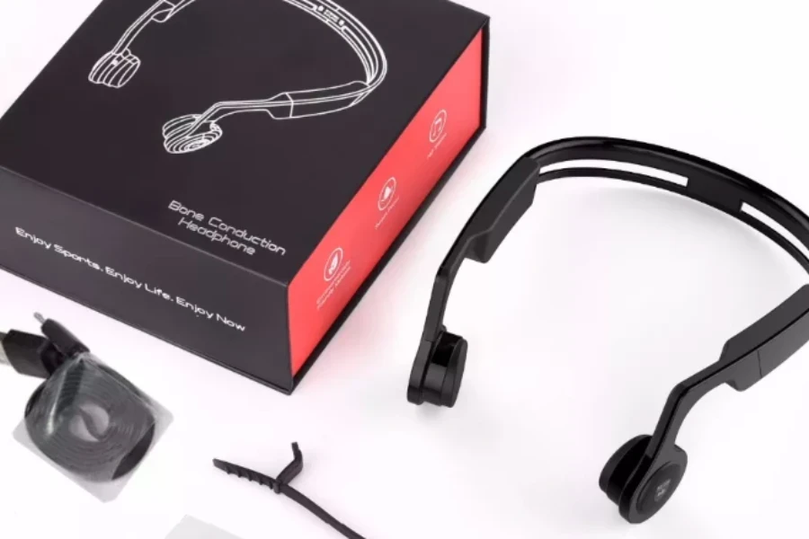 auriculares de conducción ósea negros sobre un fondo blanco junto a la caja de los auriculares