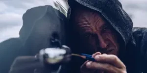 Burglar in hood trying to unlock car with lockpick