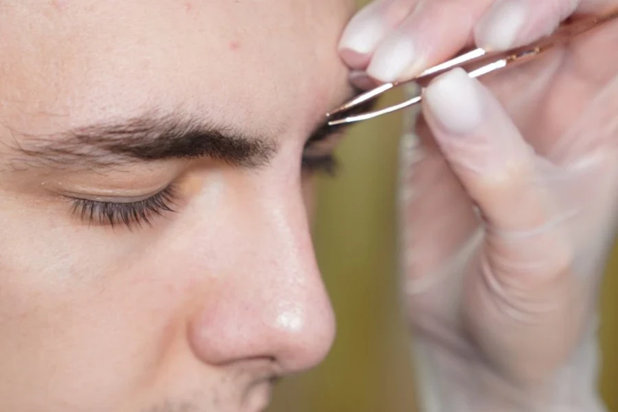 L'homme se fait tailler les sourcils avec des pincettes