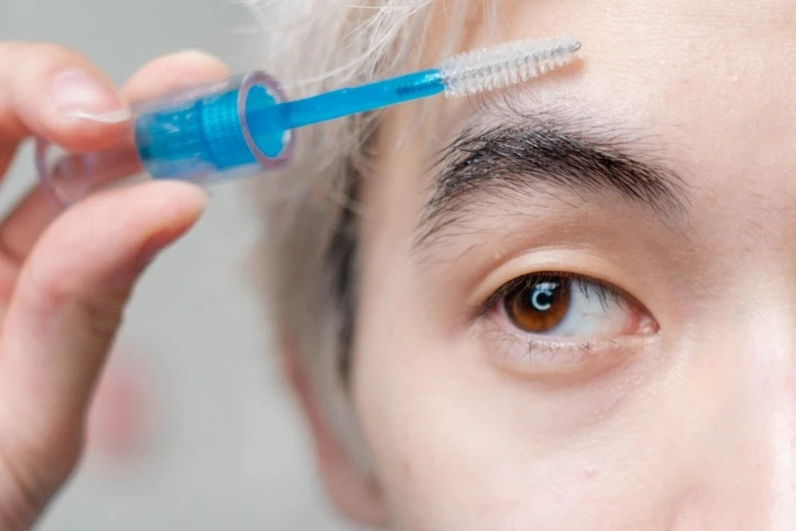 Man using a brush to prep his eyebrow for trimming