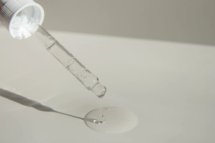 Perfume pingando de uma bomba de vidro transparente