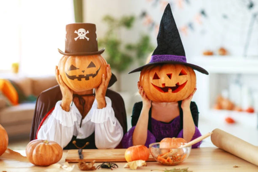 dos personas sosteniendo calabazas en la cara con sombreros