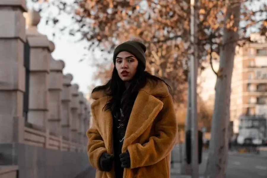 Woman in a brown mid-length weatherproof coat on the sidewalk