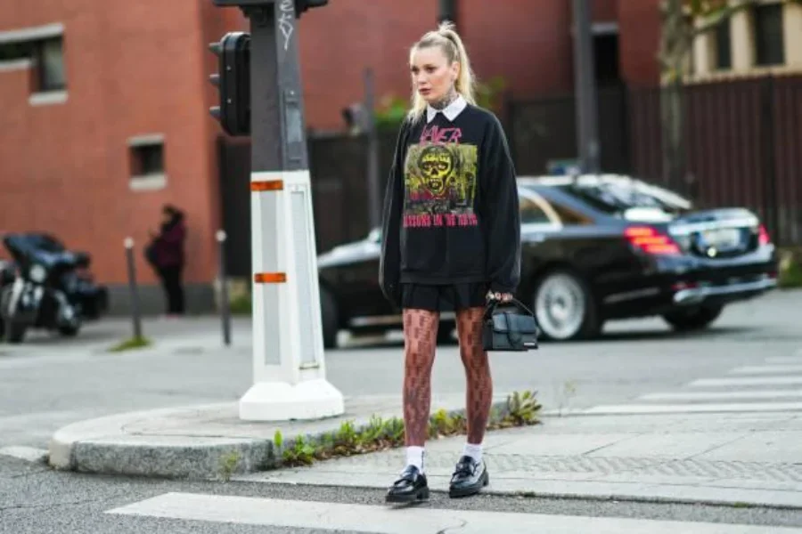 Woman wearing a black sweatshirt, fishnet stockings, and mini skirt
