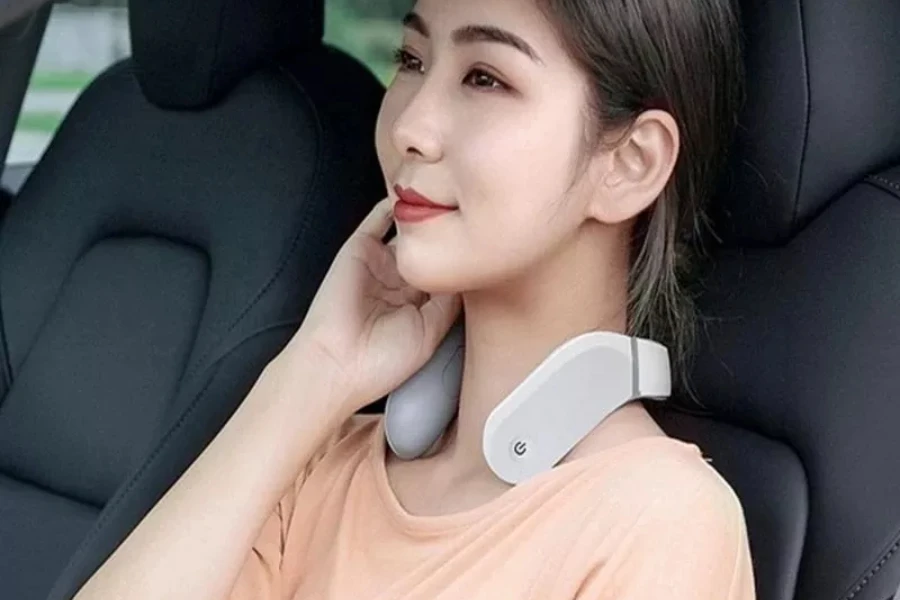 Frau trägt ein Nackenmassagegerät, während sie im Auto sitzt