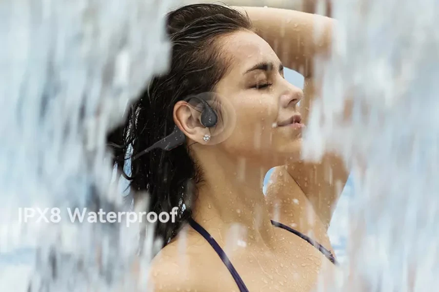 Frau mit schwarzen Knochenleitungskopfhörern unter einem Wasserstrahl