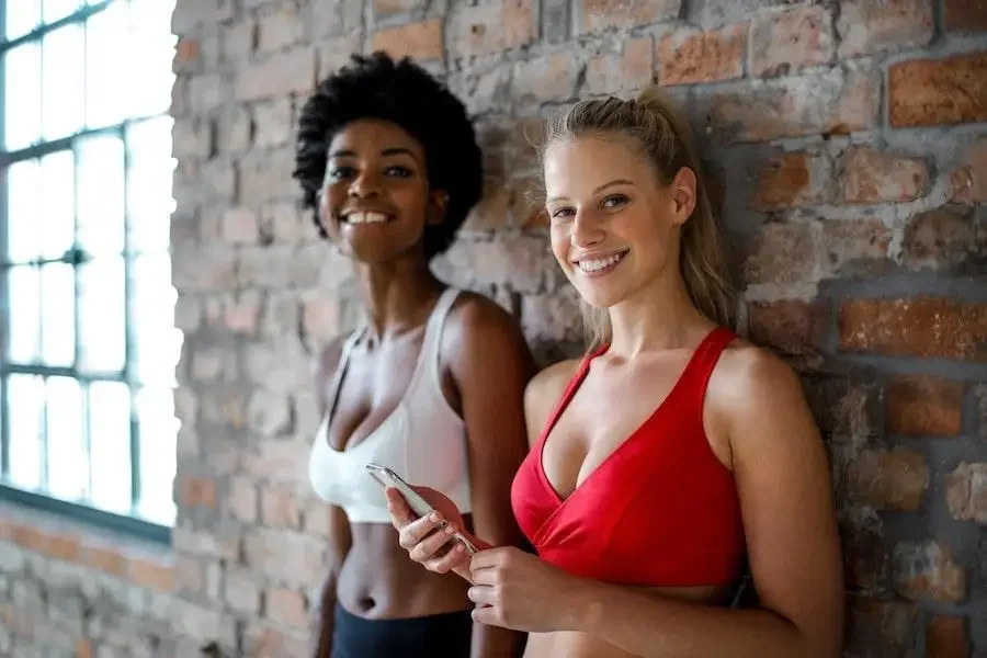 Women smiling while wearing red and white sports bras
