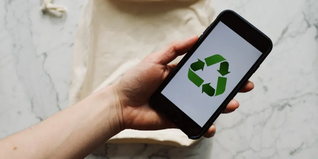 A person holding a smartphone with a recycle sign