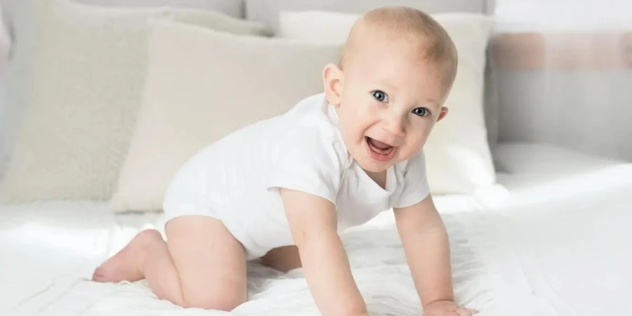 Baby wearing white bodysuit on a bed