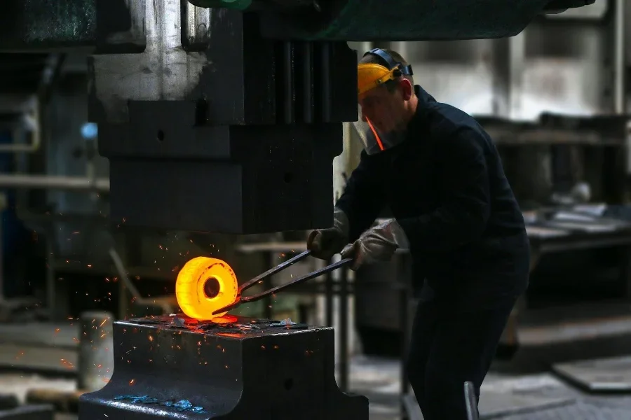 Man lifting hot metal during metal forging process