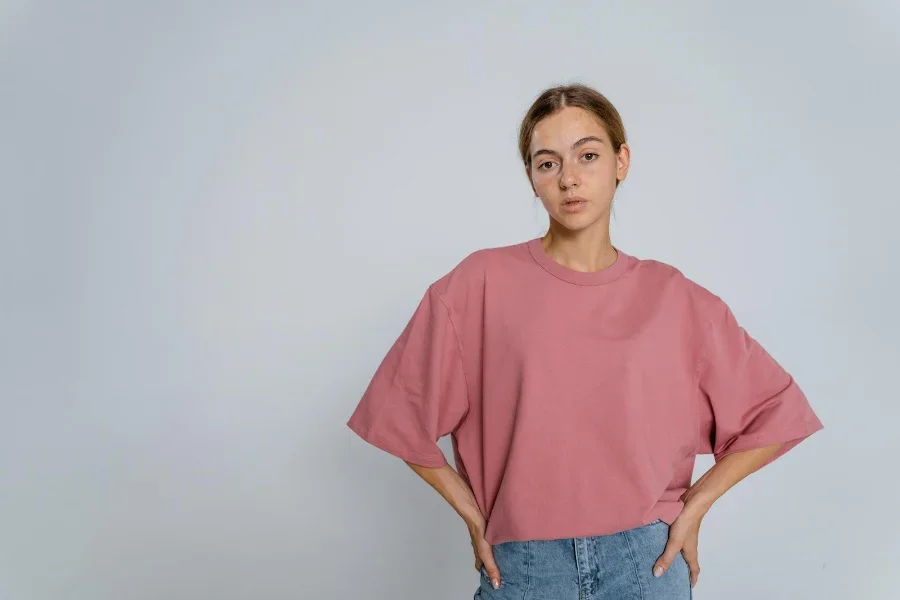 Wanita dengan celana jeans biru mengayunkan polo berwarna lembayung muda