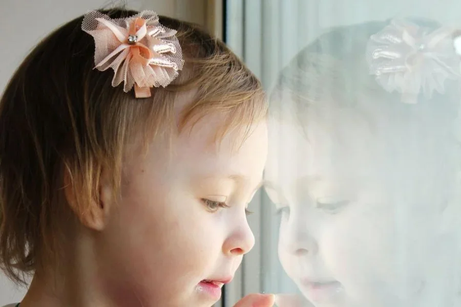 A little girl wearing an orange hair clip