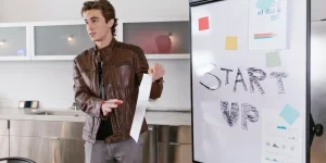 A man holding a paper while presenting in front of a board to crowdfund for start-up