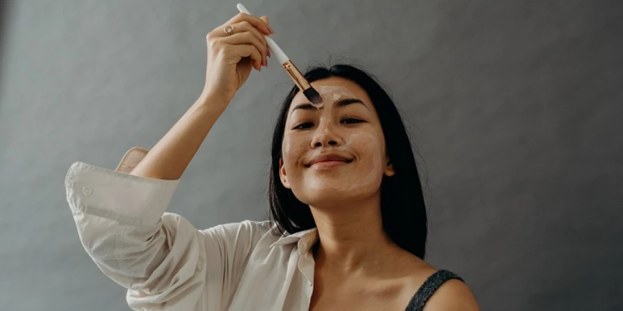 A woman using a makeup brush to apply cream on her face