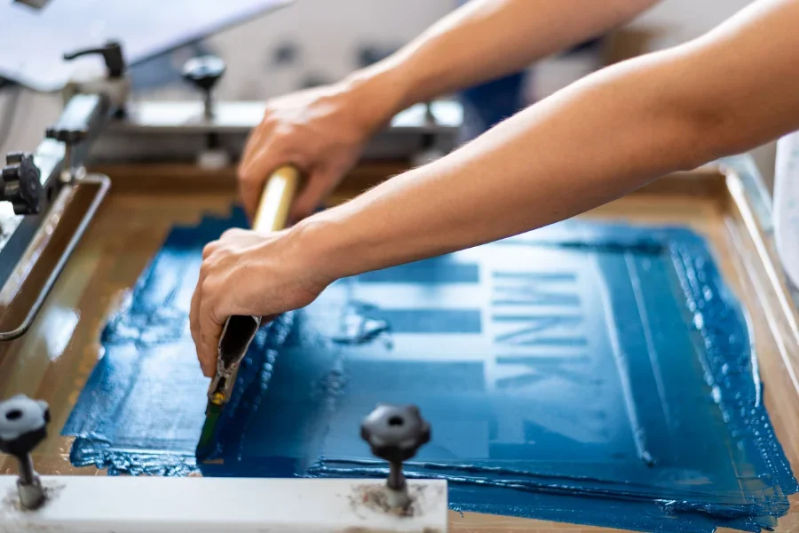 Person using a screen printer on textiles
