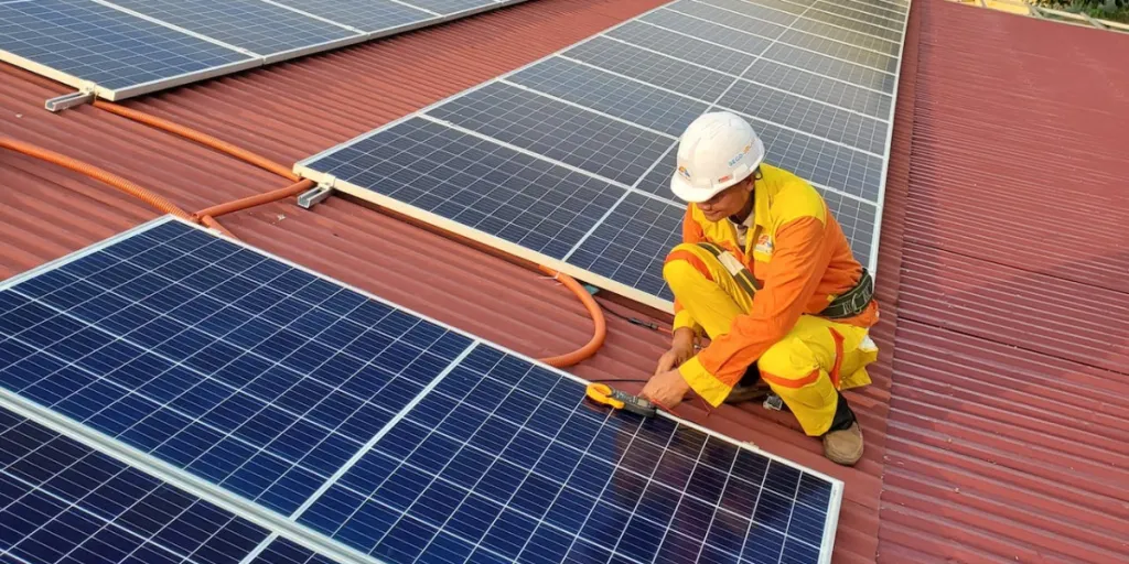 Seorang teknisi surya laki-laki sedang memasang panel surya