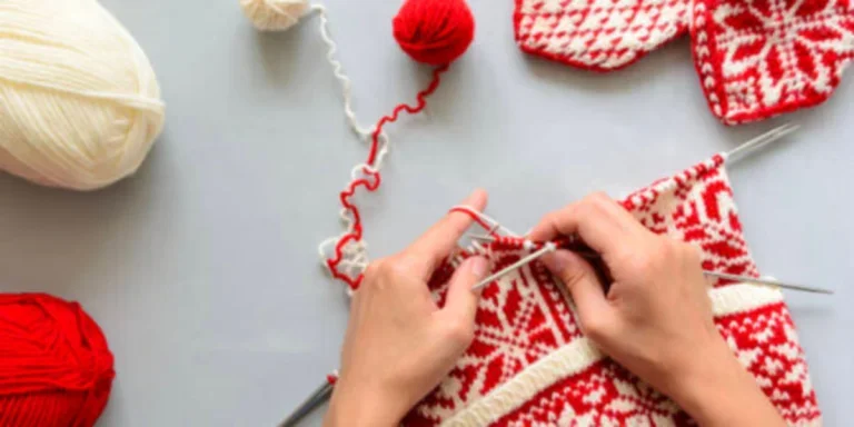 A red and white jacquard beanie being knitted