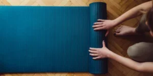 Una mujer doblando una estera de yoga después de hacer ejercicio.