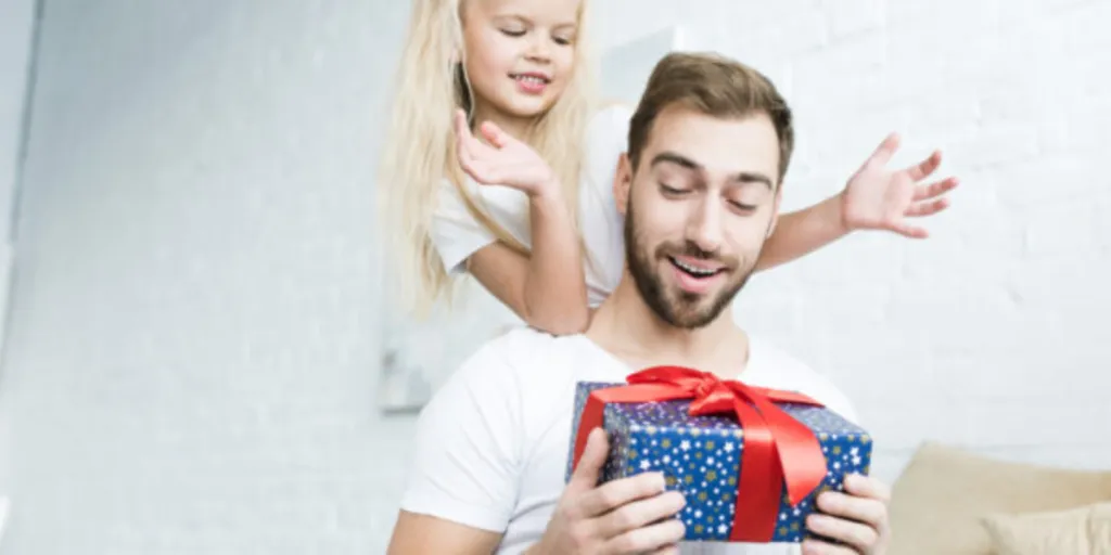 Happy daughter looking at surprised father holding gift box