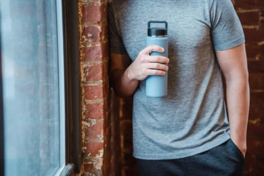 Mann hält eine Wasserflasche im Sportstudio