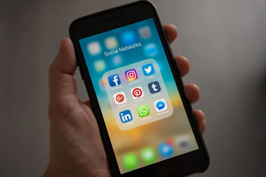 Sosyal ağlar klasörü açıkken iPhone'u tutan kişi