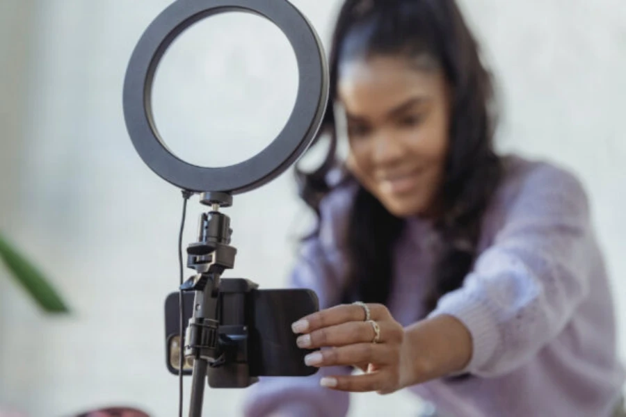 Woman setting up smartphone with ring light to make content